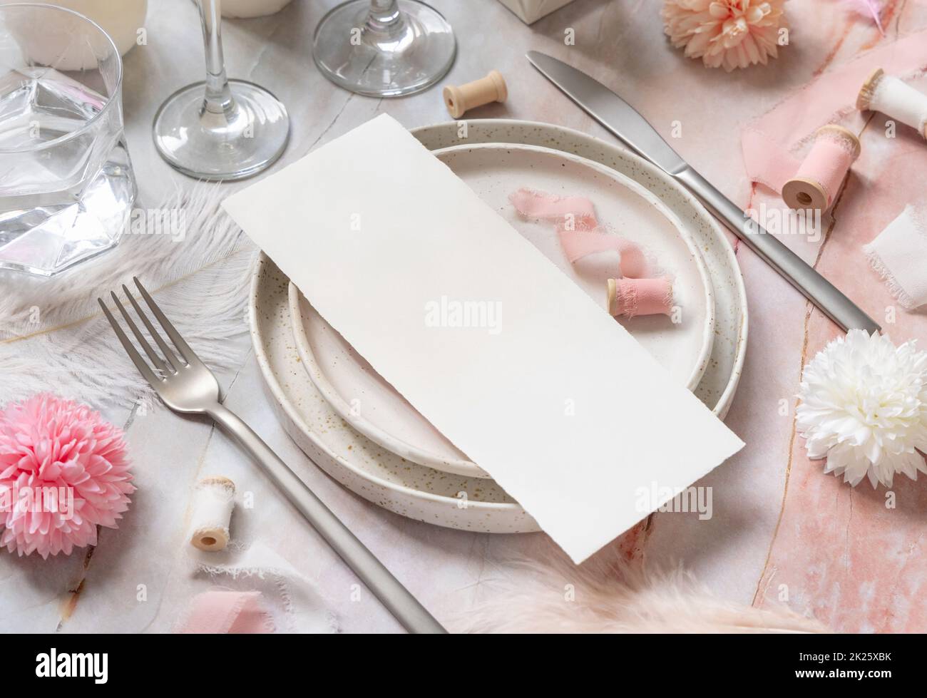 Wedding Table place with a card near pink flowers, feathers and silk