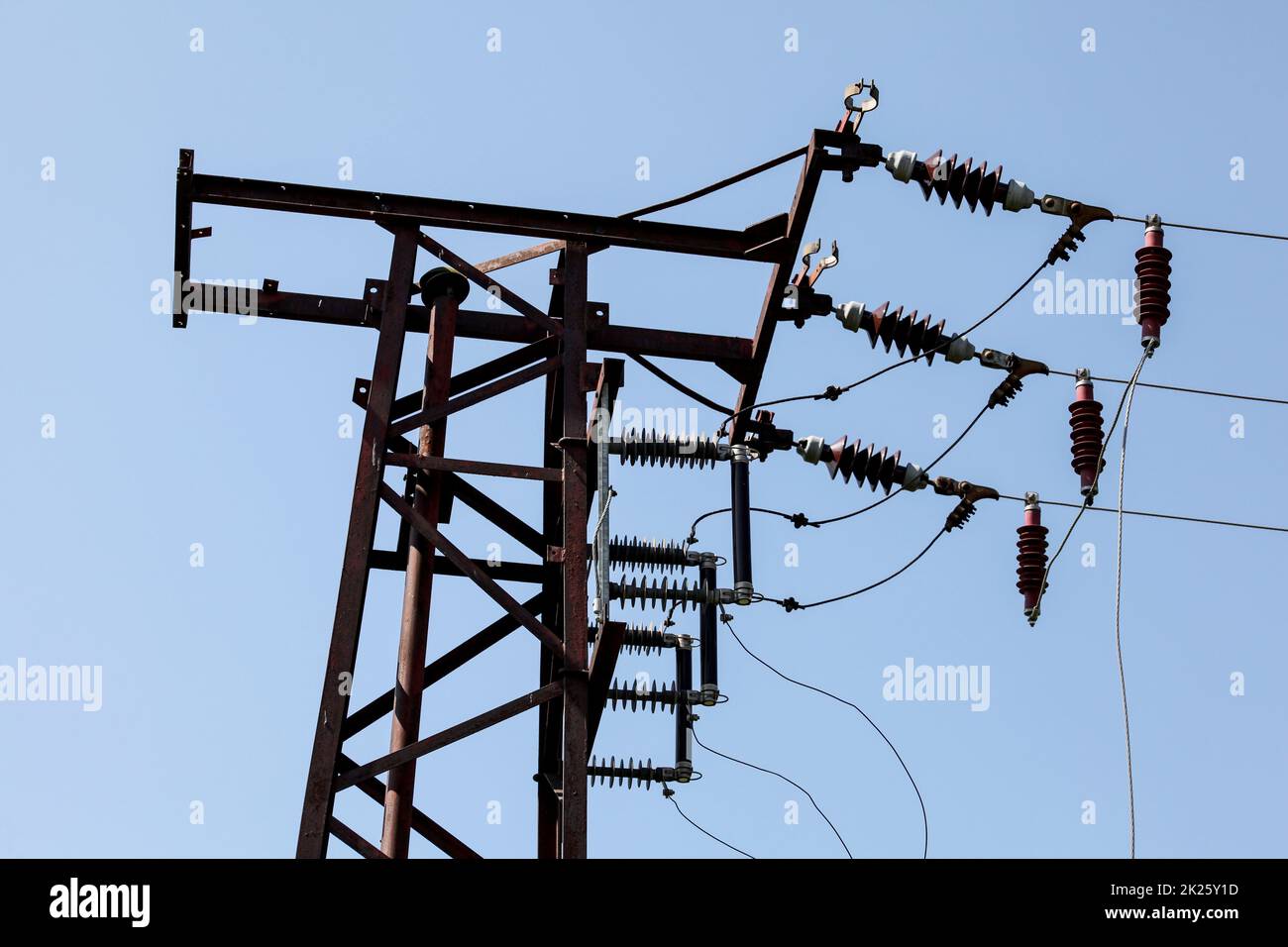 Top of electrical transformer pylon, photo of electric wires against blue sky. Stock Photo