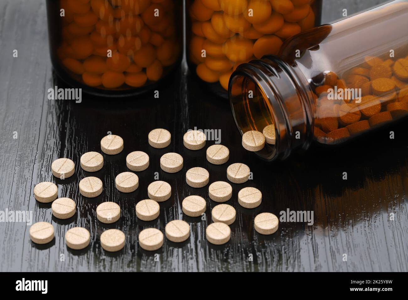 medical pills and brown glass bottle on black wooden table Stock Photo