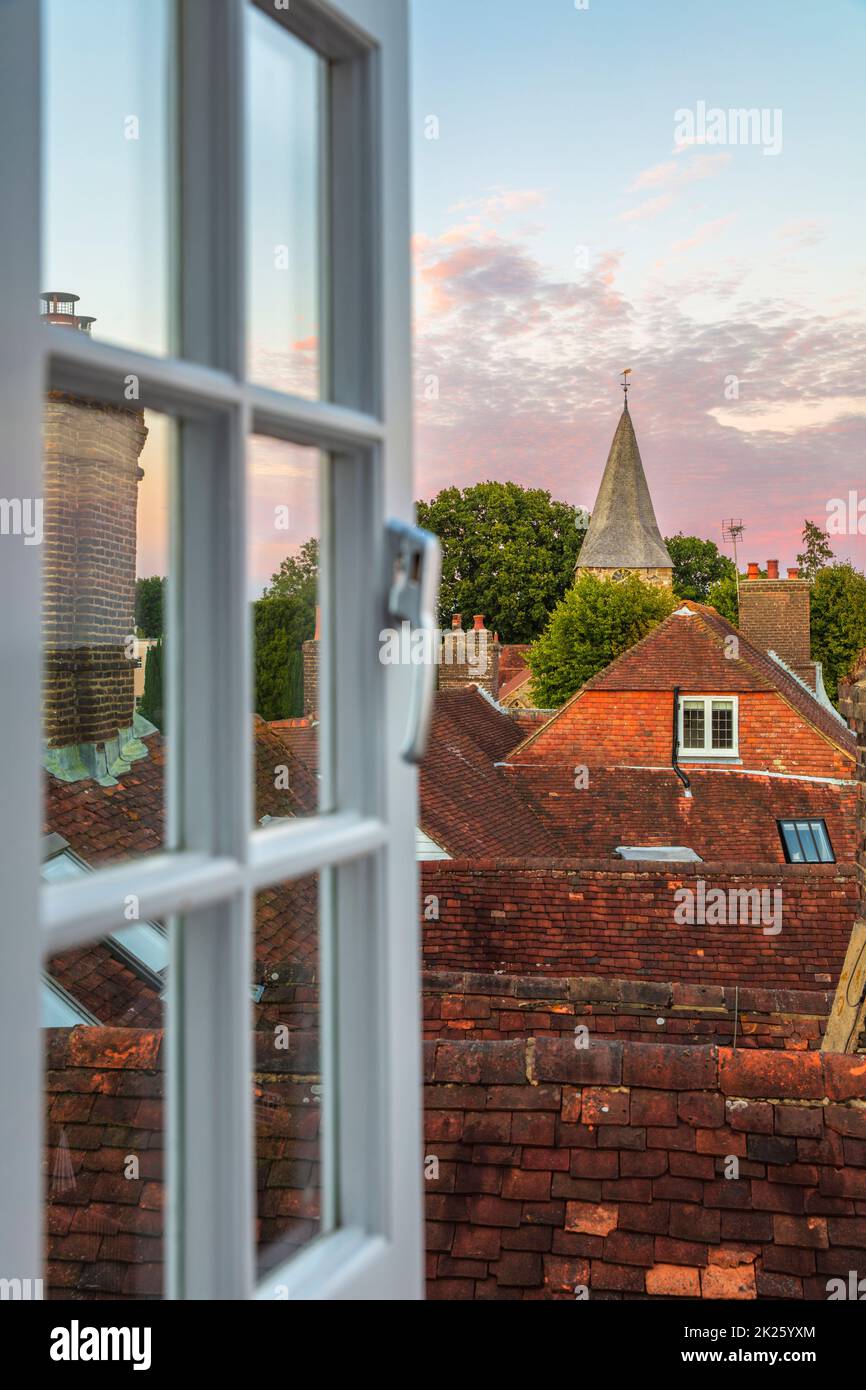 St Bartholomew's church and rooftops of Burwash viewed through open window at sunset, Burwash, East Sussex, England, United Kingdom, Europe Stock Photo