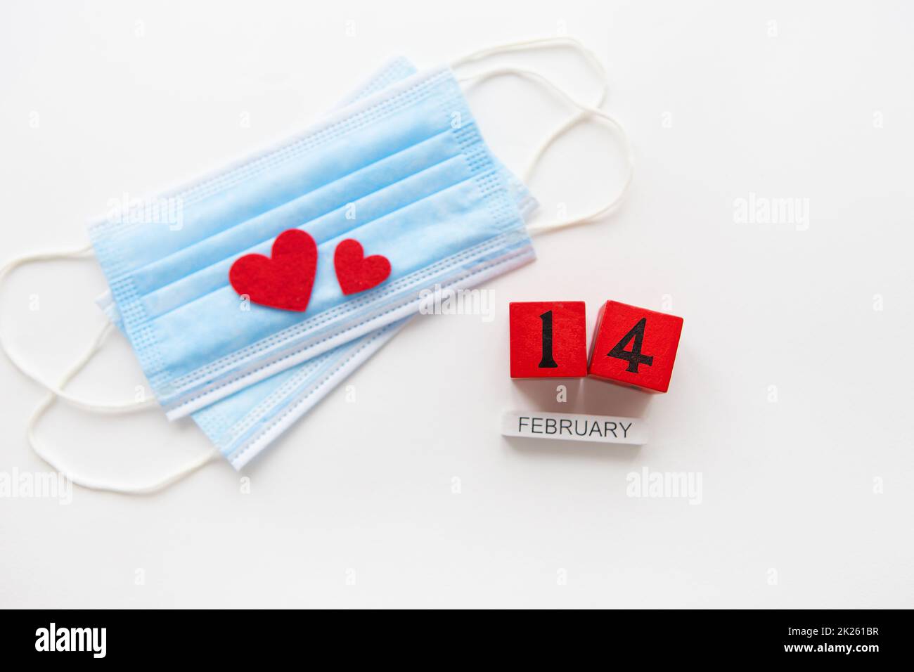 Valentine's Day celebration concept. Wooden cubes on February 14th. The heart lies on medical masks, the fight against coronavirus. Stock Photo