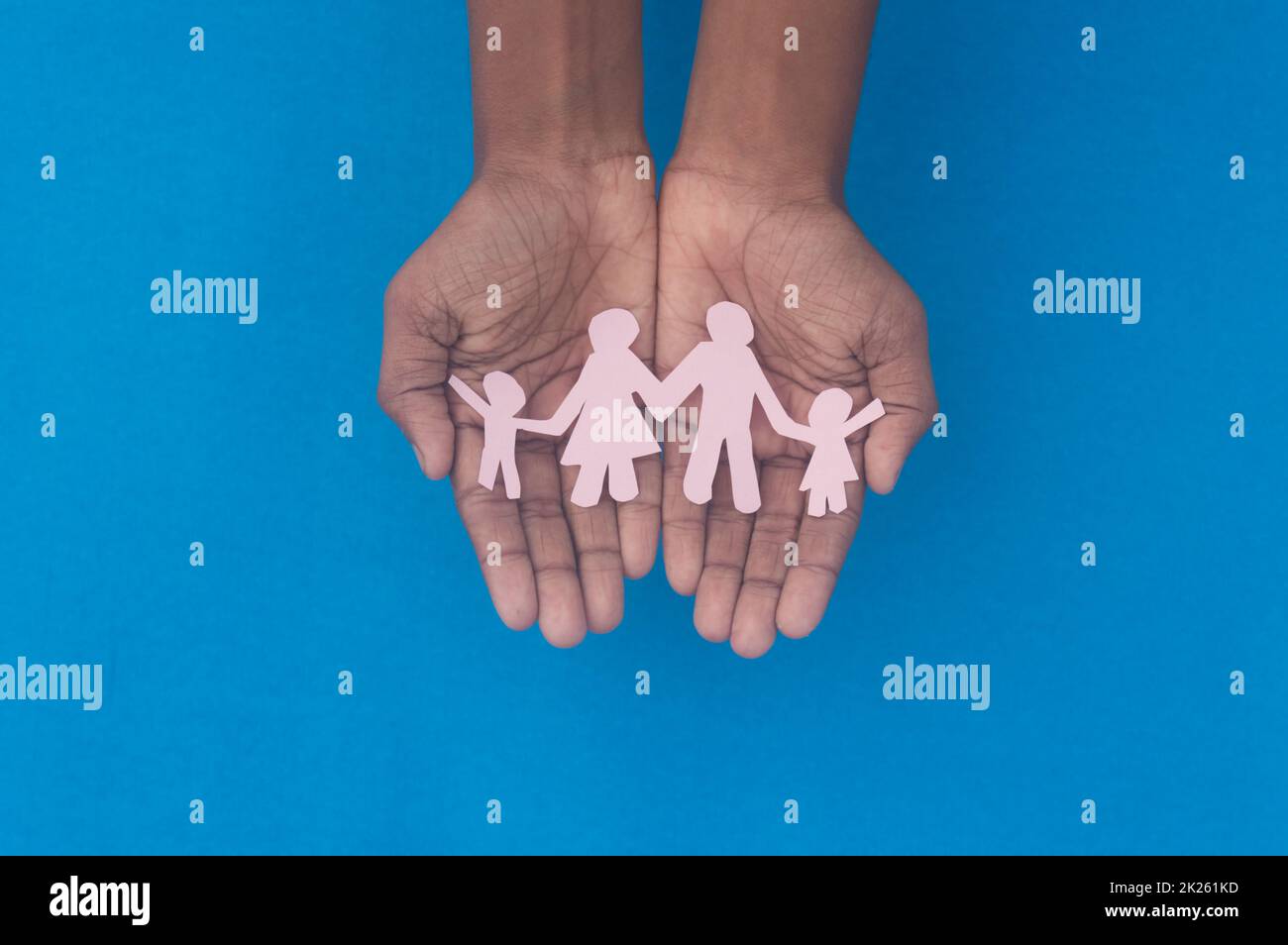 Hand holding family figure cutout top view. World health day Protection against domestic violence, healthcare and medical background. Foster care, homeless support and social distancing concept. Stock Photo