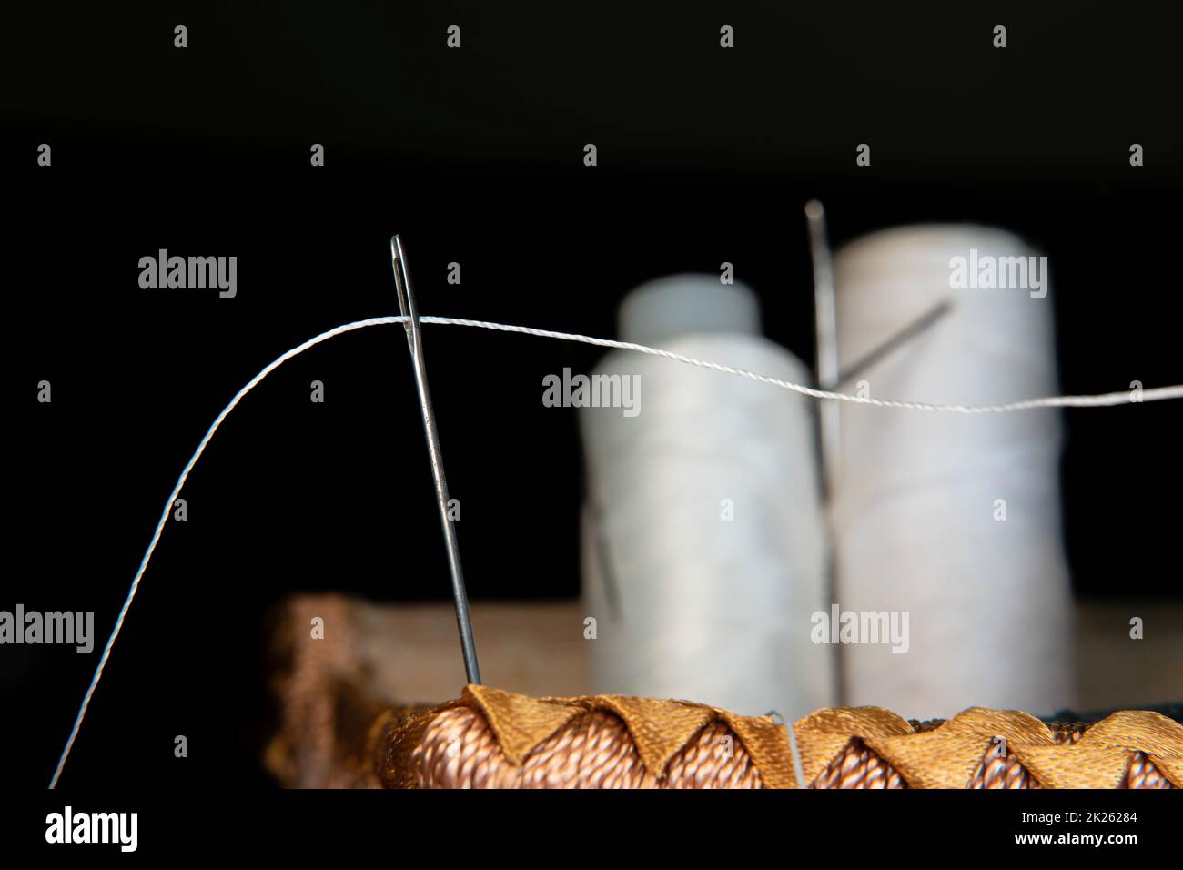 The thread is threaded through the eye of a sewing needle.Sewing and