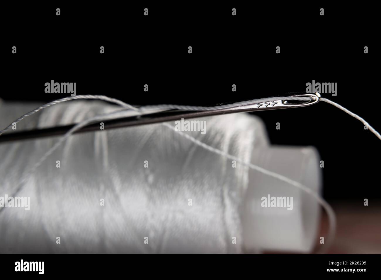 The thread is threaded through the eye of a sewing needle.Sewing and