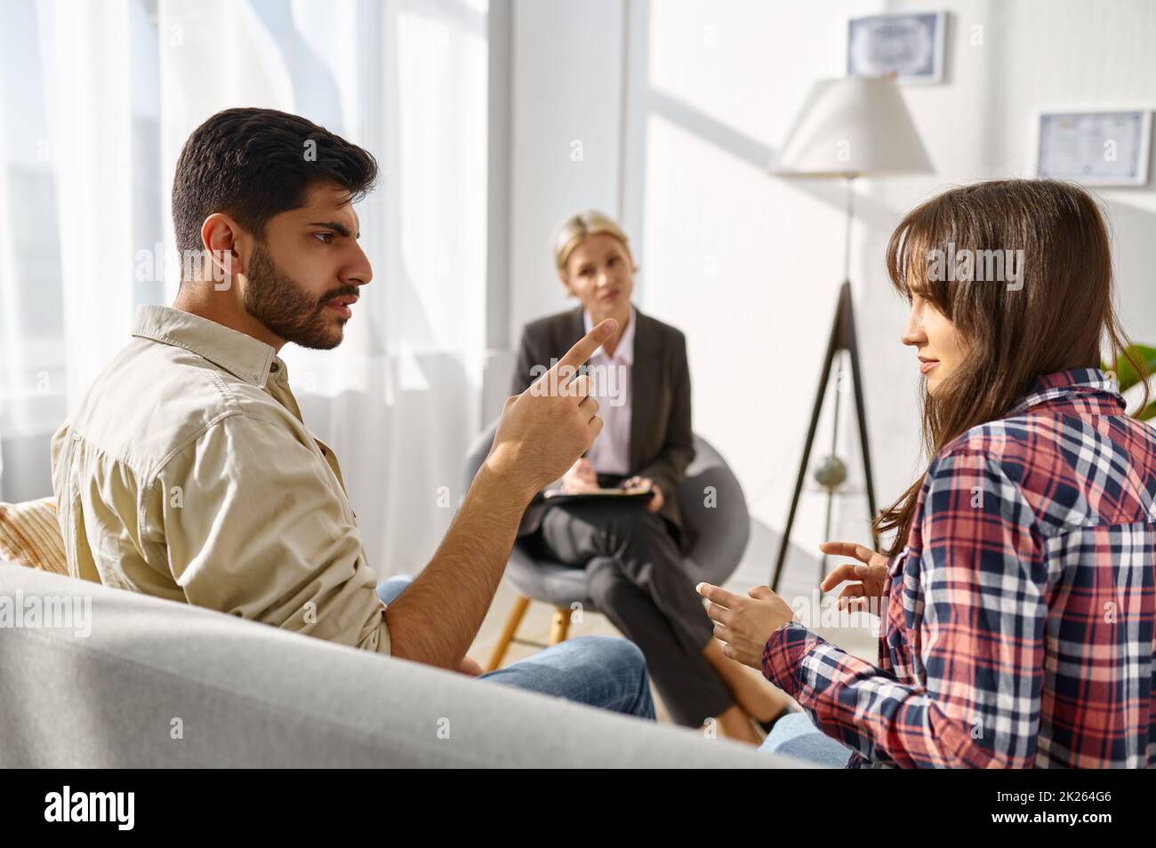 Unhappy couple arguing disagreement at psychologists office Stock Photo