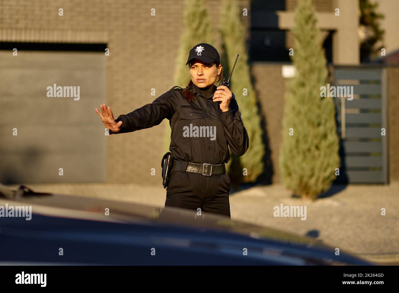 Police woman using walkie-talkie controlling road traffic Stock Photo