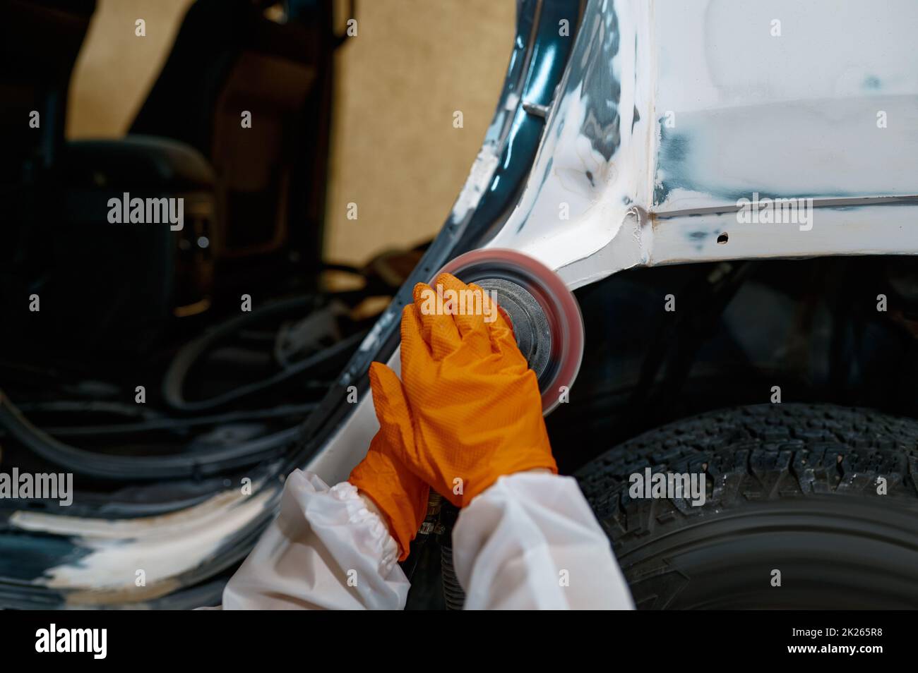 Auto painter polishing plastered car body part Stock Photo