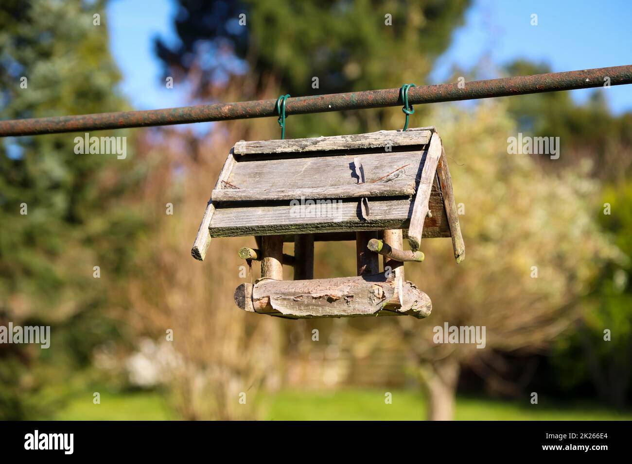 A wooden birdhouse attached to a metal pole. Stock Photo