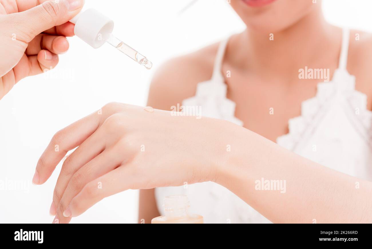 Beautiful woman dropping serum collagen moisturizer into back of the hand Stock Photo