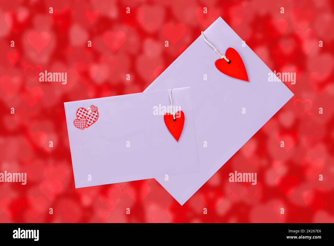 Happy Valentine or Mothers Day card template. 3D illustration of two envelopes with red hearts made of wood over abstract red background with hearts. Space for text design. Stock Photo
