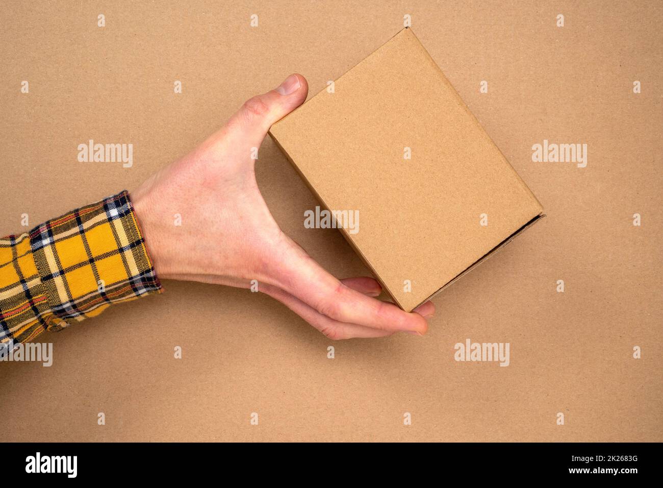 Hand with brown cardboard box for packaging and delivery Stock Photo