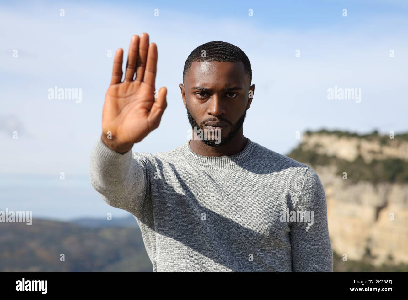 Man with black skin gesturing stop in the mountain Stock Photo