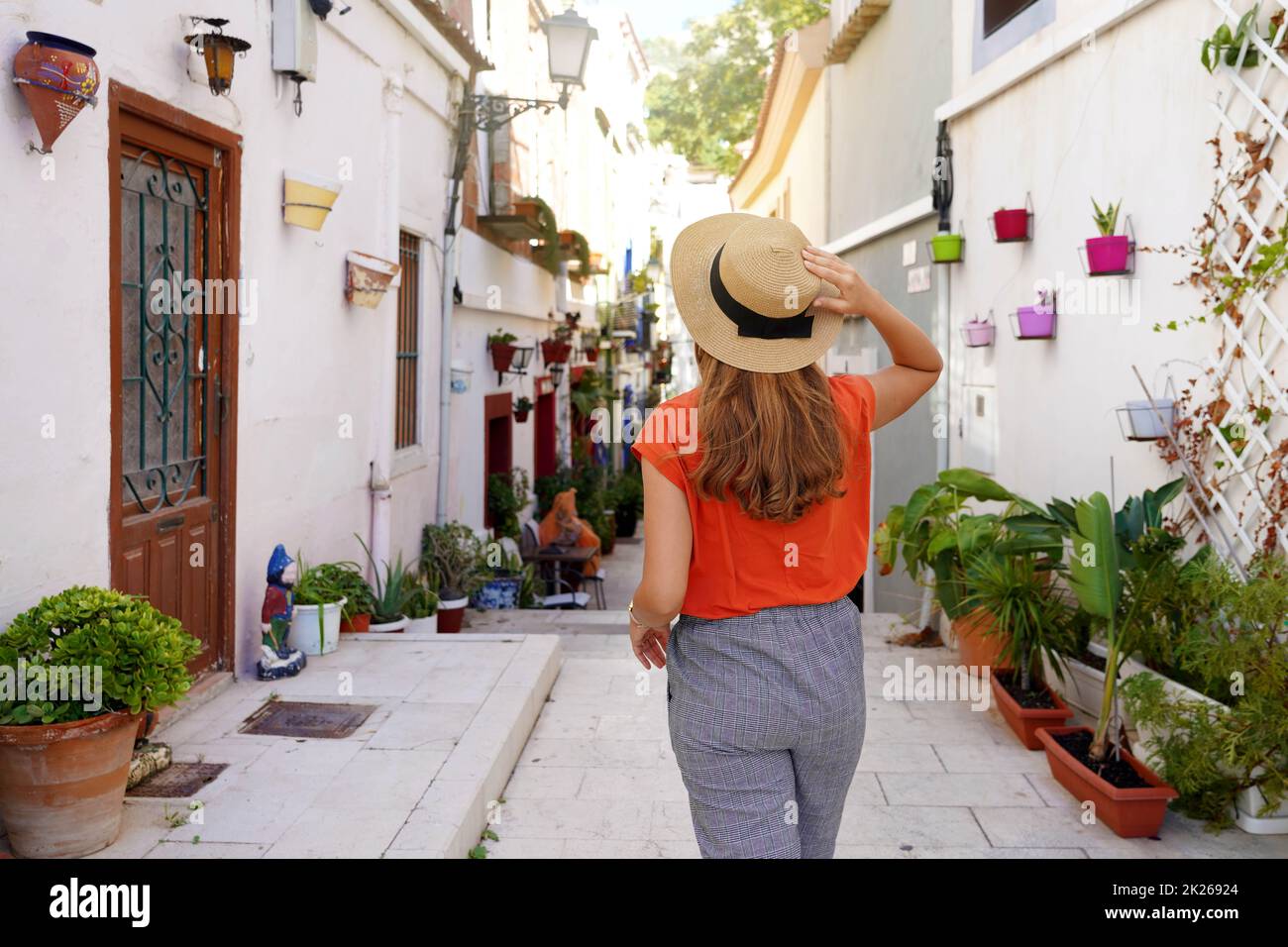 Visiting Alicante in Spain. Traveler woman visits the neighborhood Santa Cruz of Alicante in Spain. Tourist girl exploring european city with typical Mediterranean architecture and decoration. Stock Photo