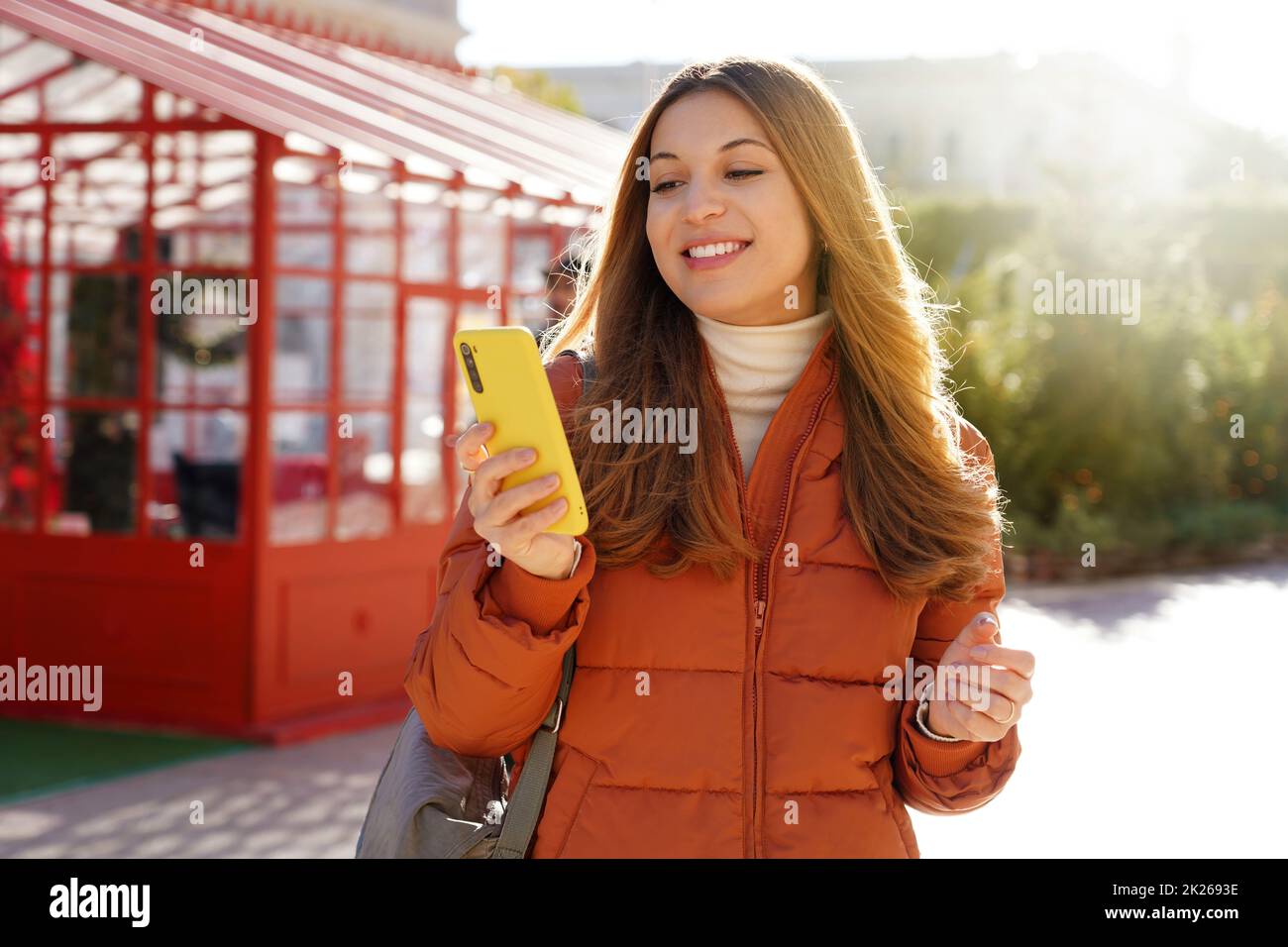 Young woman using phone walking in the city on sunny winter day Stock Photo