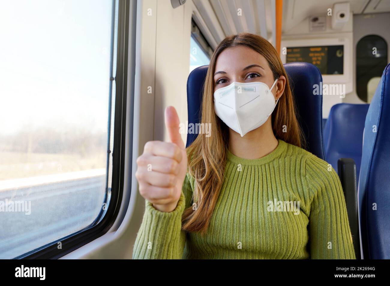Optimistic young woman wearing protective medical face mask on public