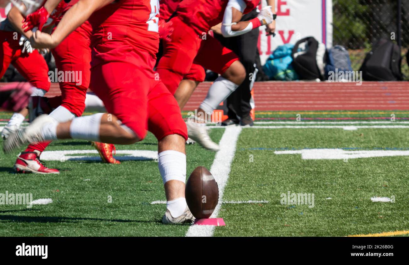 Side view of a high school football team kicking off on a turf field. Stock Photo