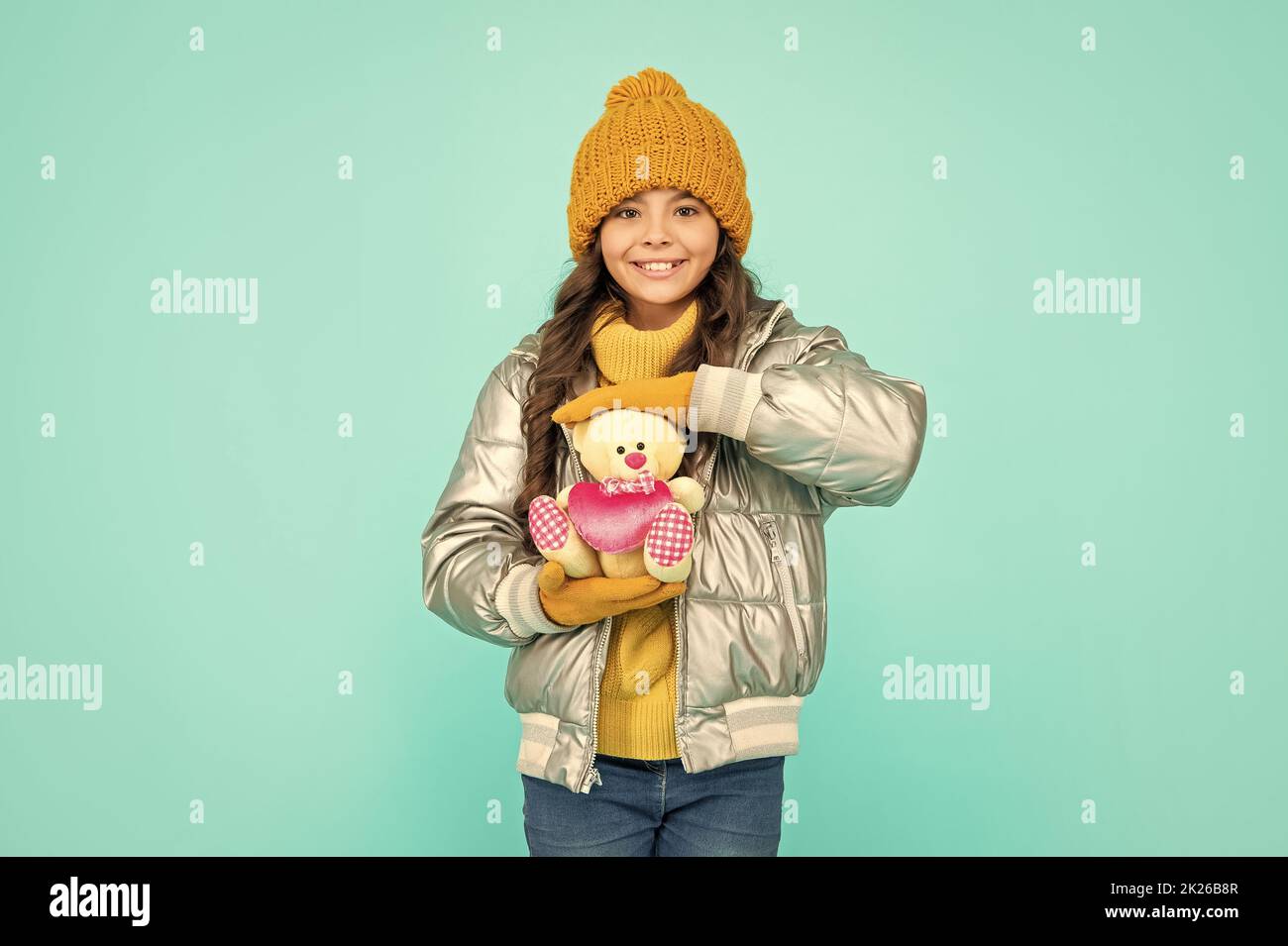 winter fashion. love toy for valentines day. happy kid in puffer jacket and hat. childhood. Stock Photo