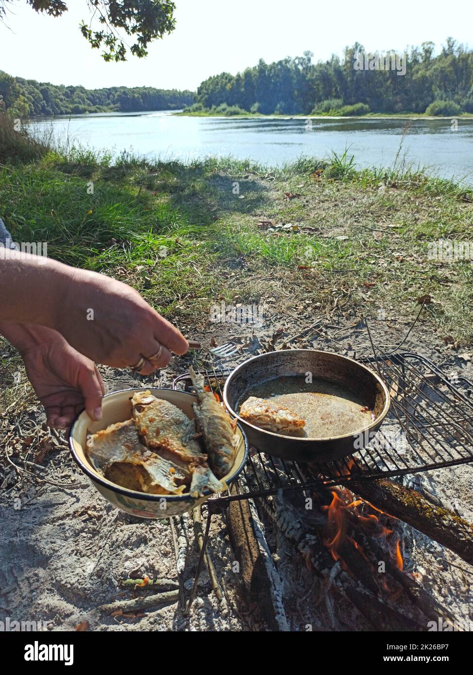 Cooking fresh fish catch. Successful fishing. Delicious dish fried over fire Stock Photo