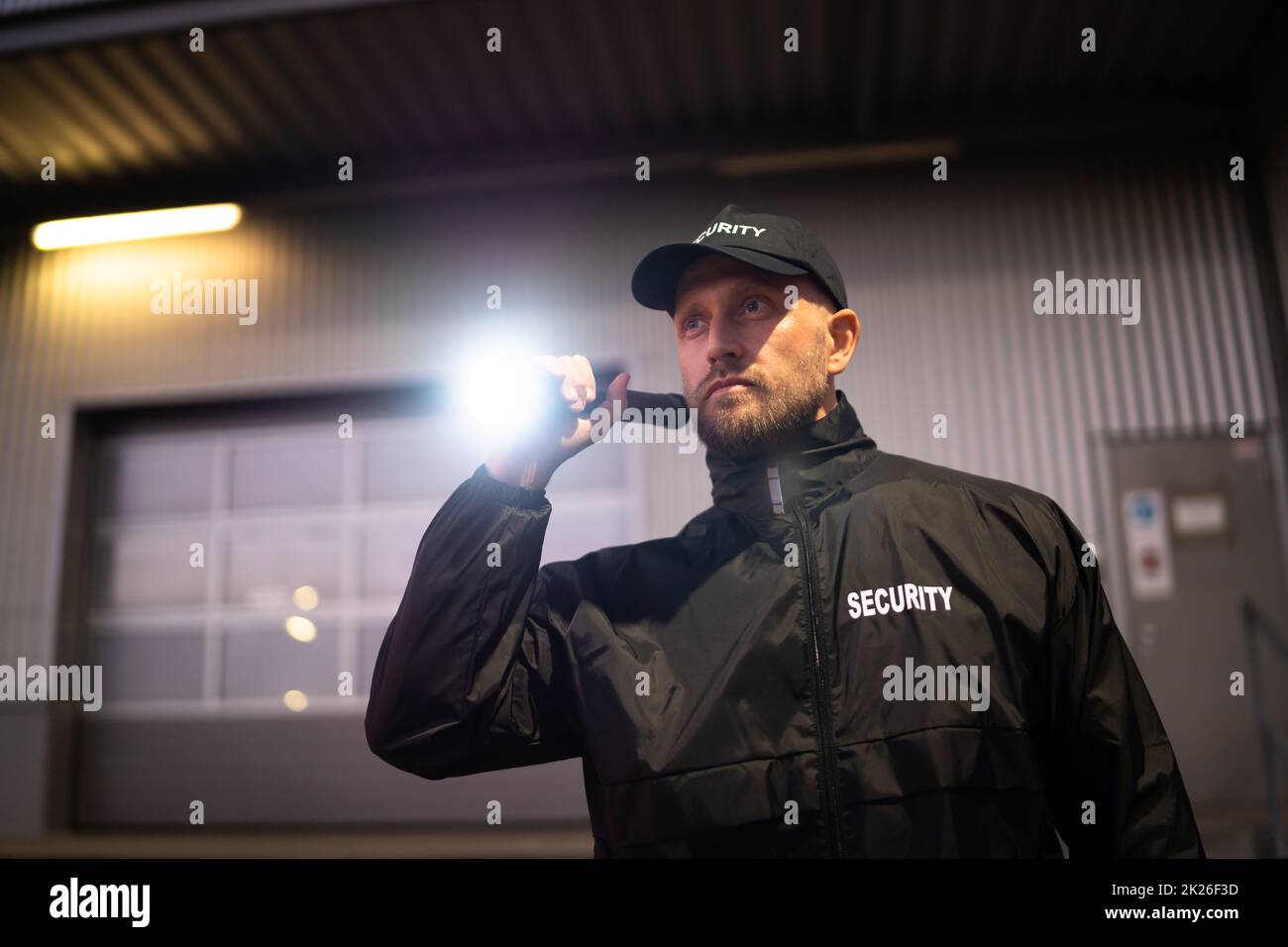 Security Guard Walking Building Perimeter With Flashlight Stock Photo