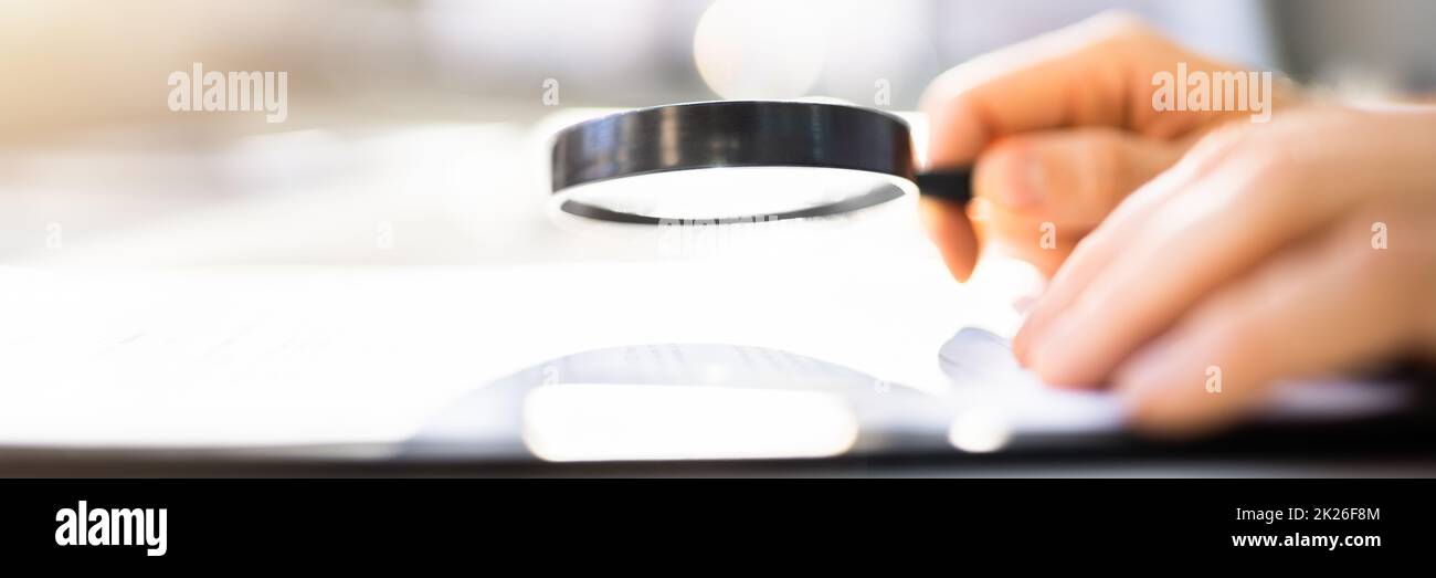 Businessman Looking At Document Through Magnifying Stock Photo