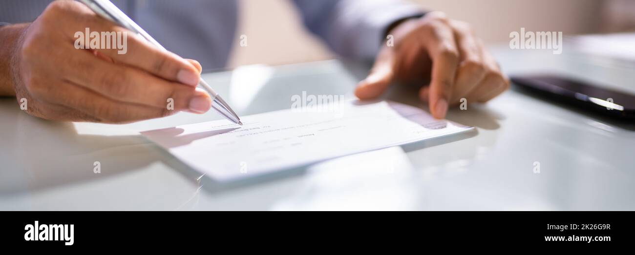 African Man Writing Money Cheque. Sign Check Stock Photo