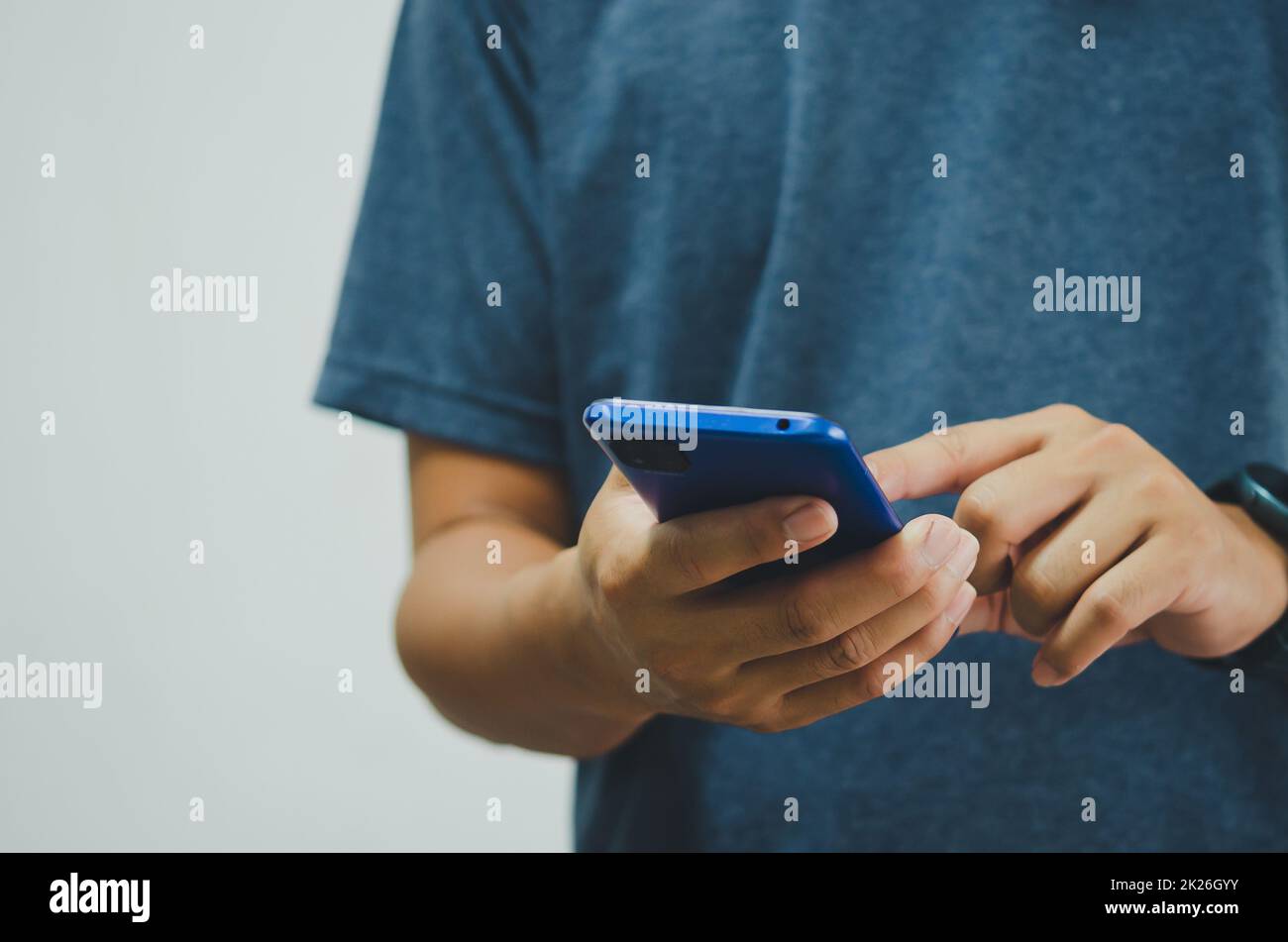 man in a blue shirt is pressing a mobile phone on background. copy space Stock Photo
