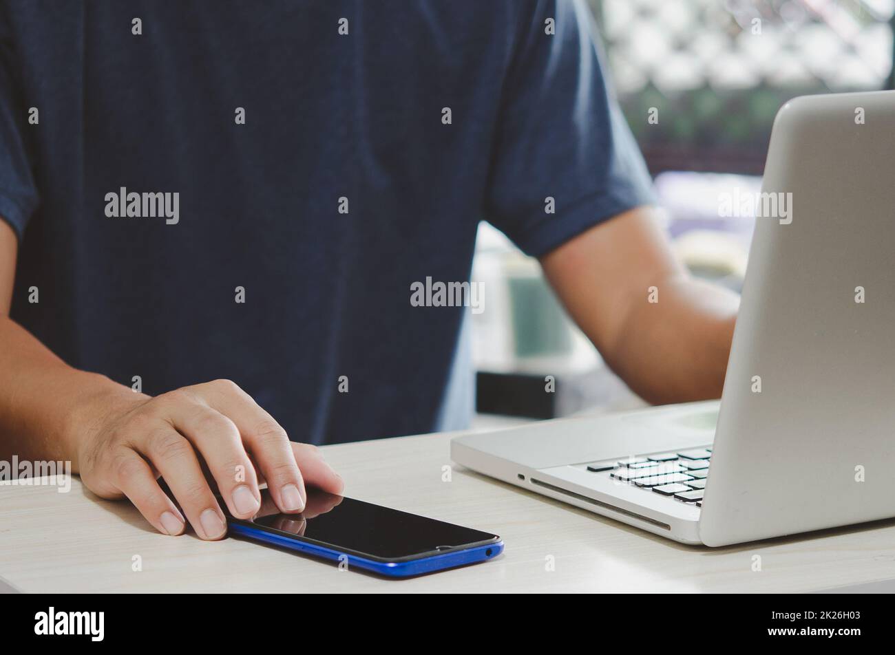 man working at computer desk pressing mobile phone Stock Photo