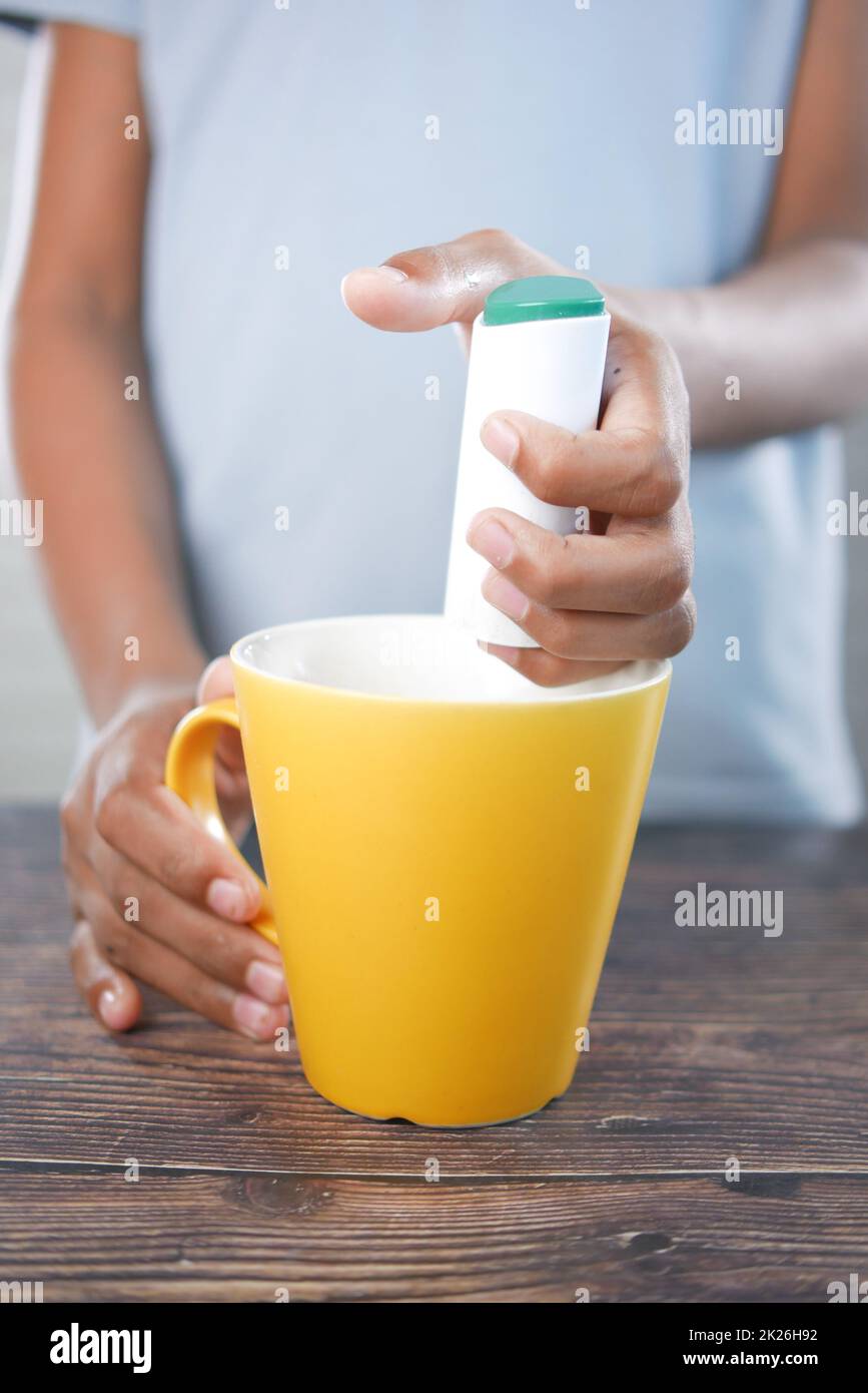 young man putting artificial sweetener in tea, Stock Photo