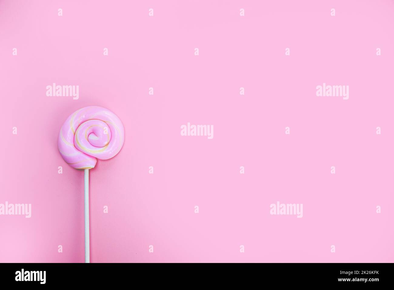 Colorful spiral lollipop on pink background top view, hard candy, sugar