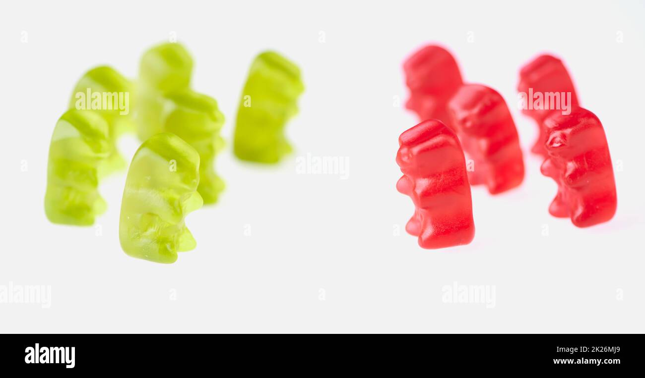 green gummy bears on the left and red gummy bears on the right side on white background Stock Photo