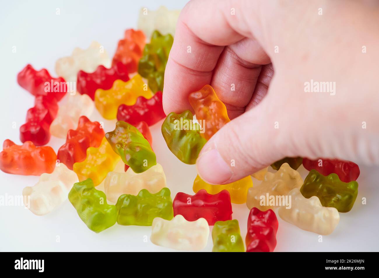 woman hand taking away two gummy bears from a pile Stock Photo