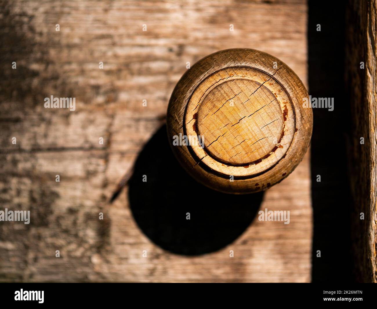 Old round wooden doorknob with light shadow. Stock Photo