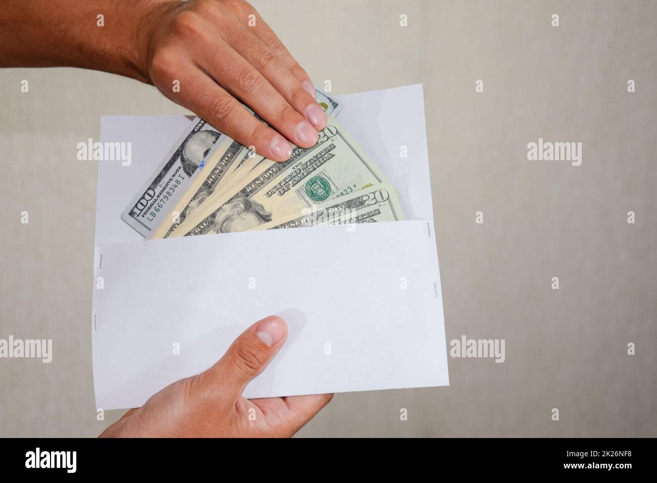 Money in a white envelope in the hands of a man. Dollars, a wad of