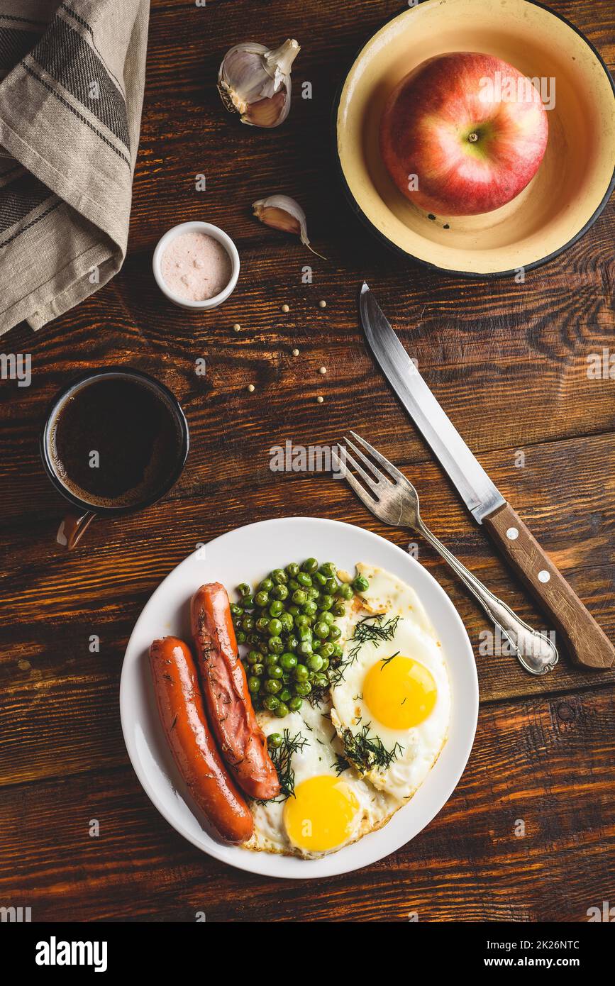 Breakfast with fried eggs, sausages and green peas Stock Photo