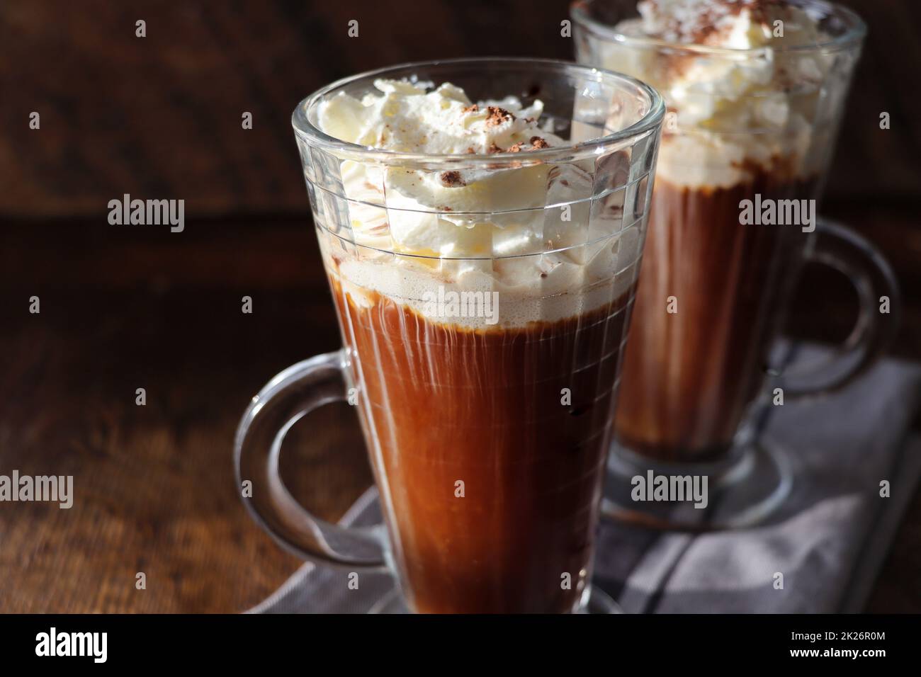 Coffee with Irish whiskey and whipped cream in glass on rustic wooden
