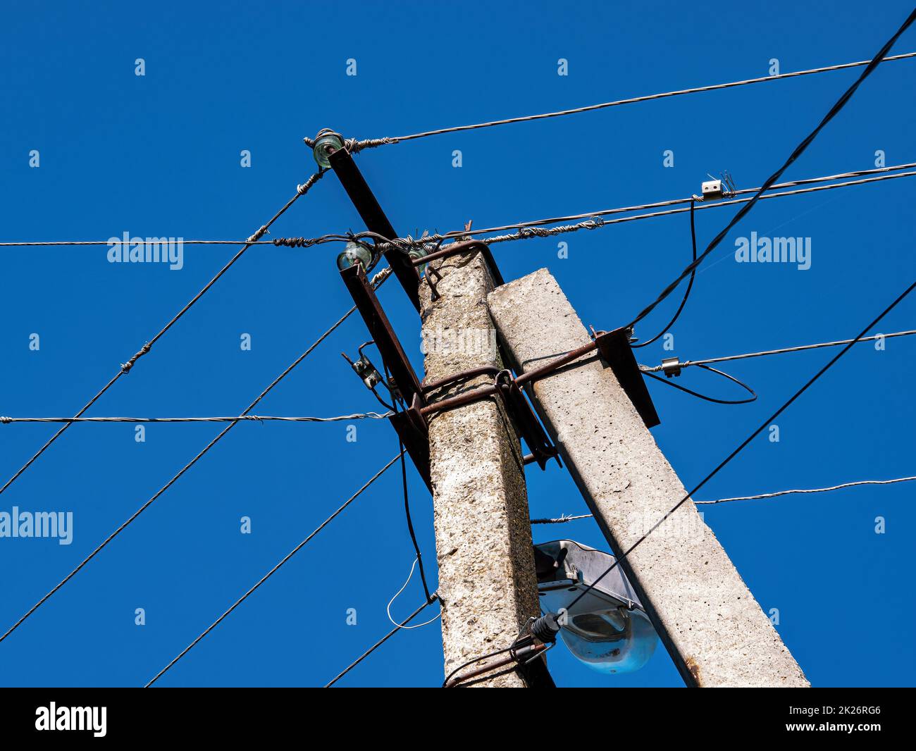 Concrete pole with electric wires against the blue sky. Stock Photo
