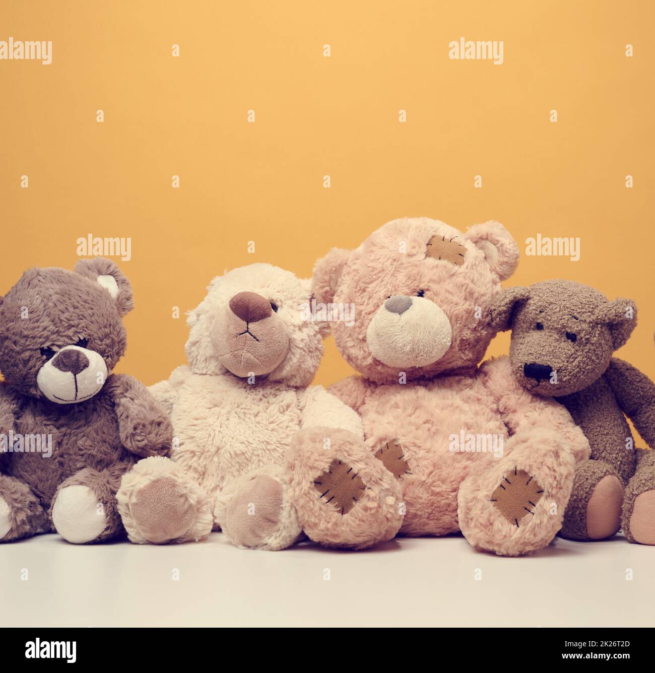 group of cute brown teddy bears sit on yellow background, childrens toy Stock Photo