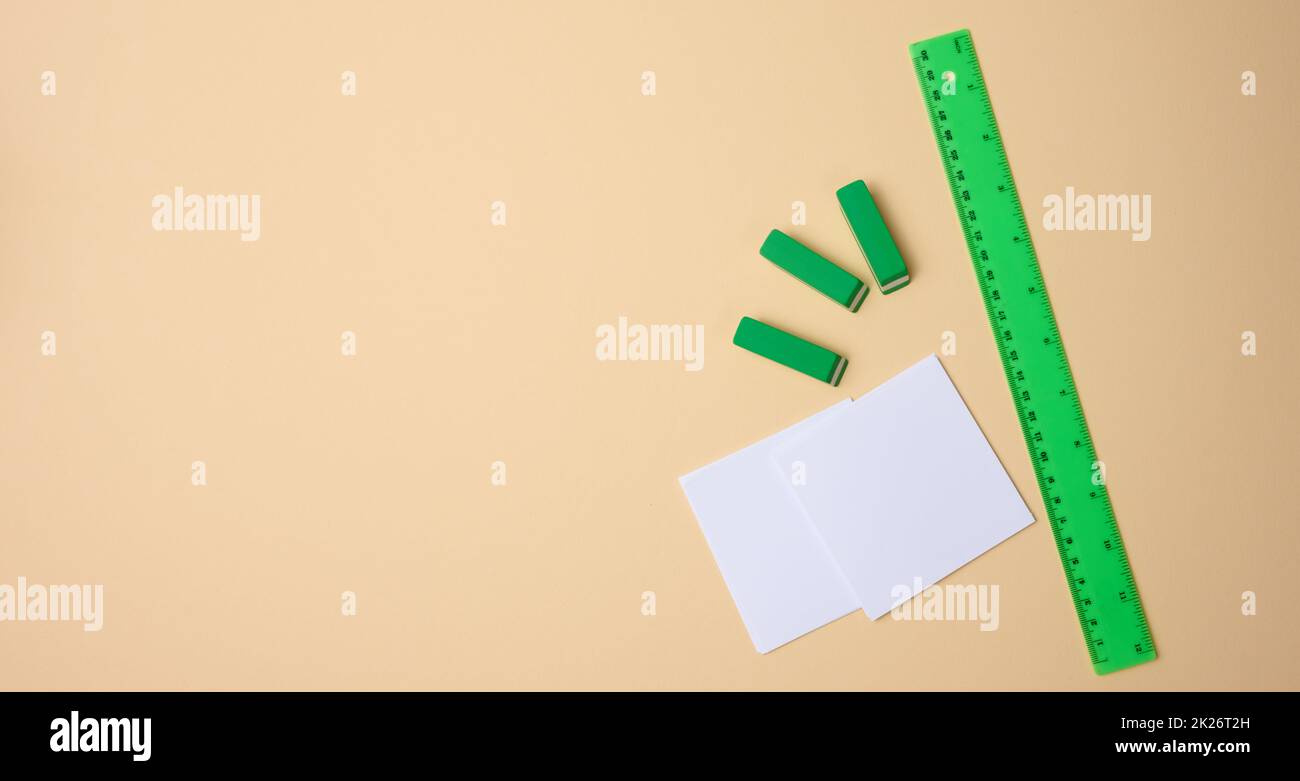 set of stationery objects ruler, blank white paper sheets ina beige background. View from above Stock Photo