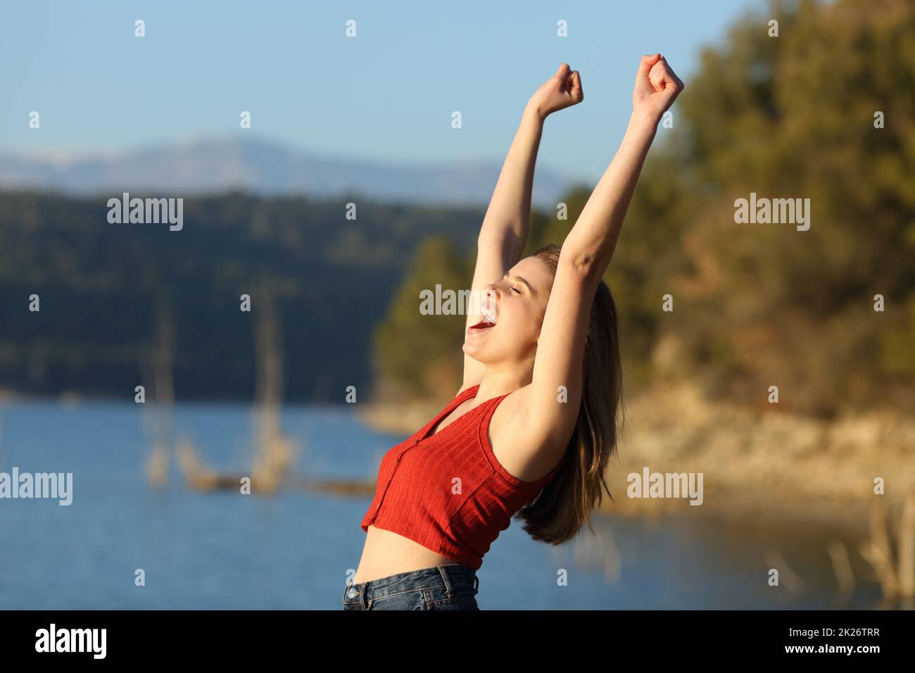 Excited woman in red celebrating vacation in nature Stock Photo