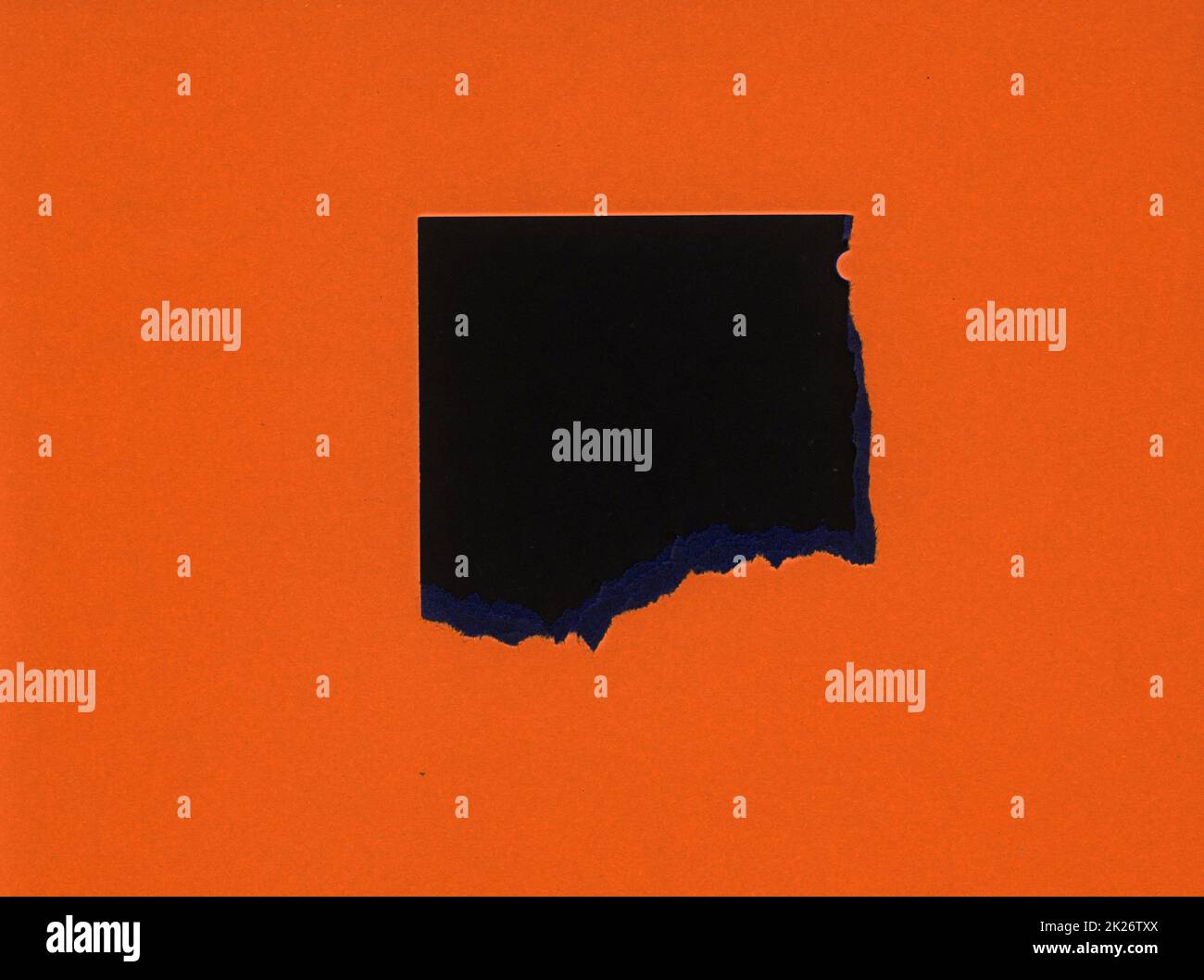torn orange paper with black hole Stock Photo