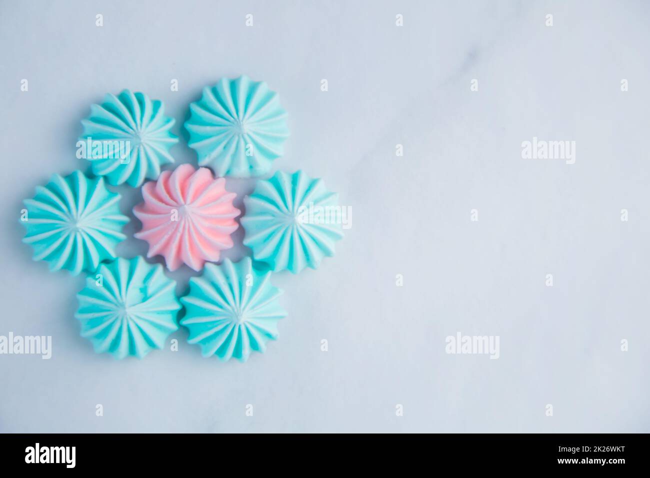 A flower with turquoise petals and a pink core made of meringue lies on a light marble background with a place for text Stock Photo