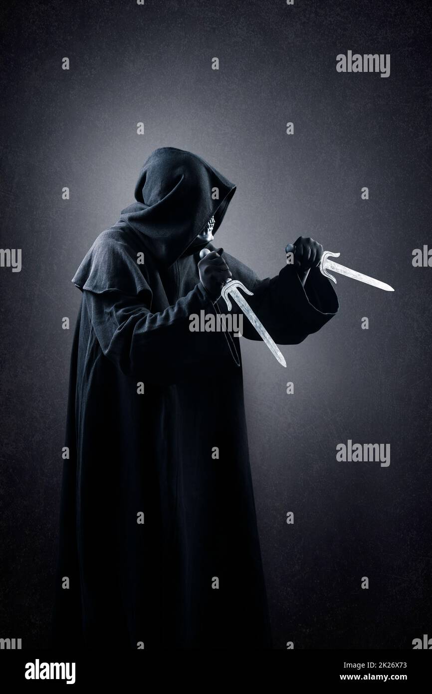 Hooded assassin with two daggers in the dark Stock Photo