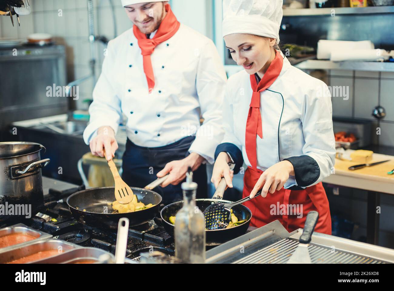 Team of chefs in a kitchen preparing fantastic food in pans Stock Photo