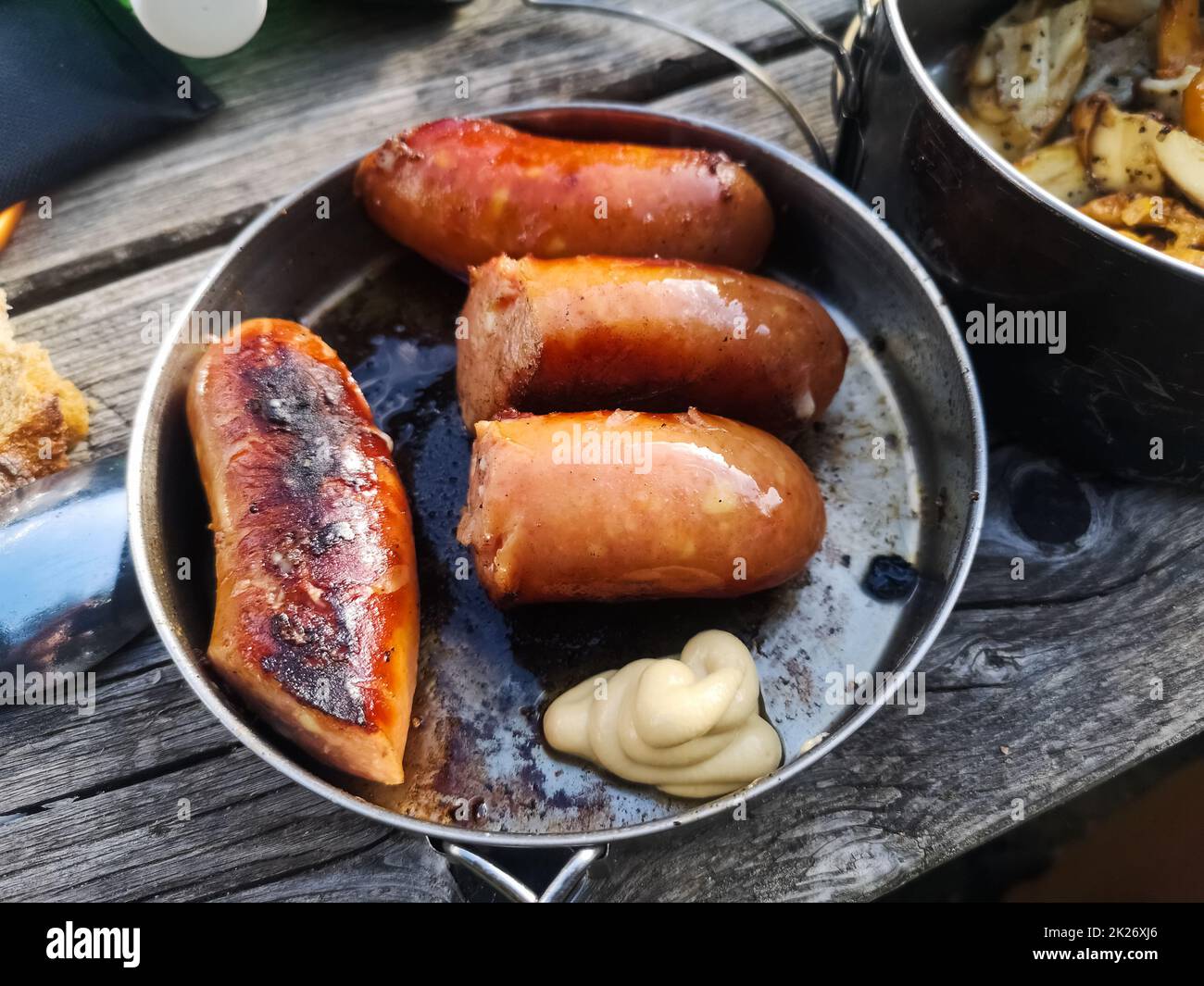 cooking outdoor food with fried sausage in a pot during hiking Stock Photo