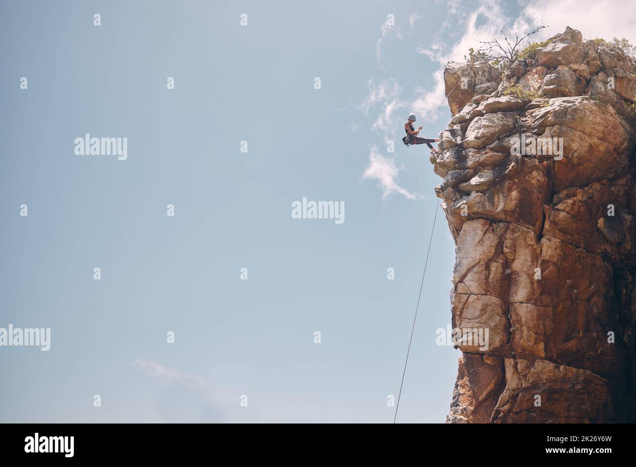 Mockup blue sky, mountain climbing woman and rock wall fearless hiking on abseiling training rope outdoor. Healthy fitness risk, adventure freedom Stock Photo