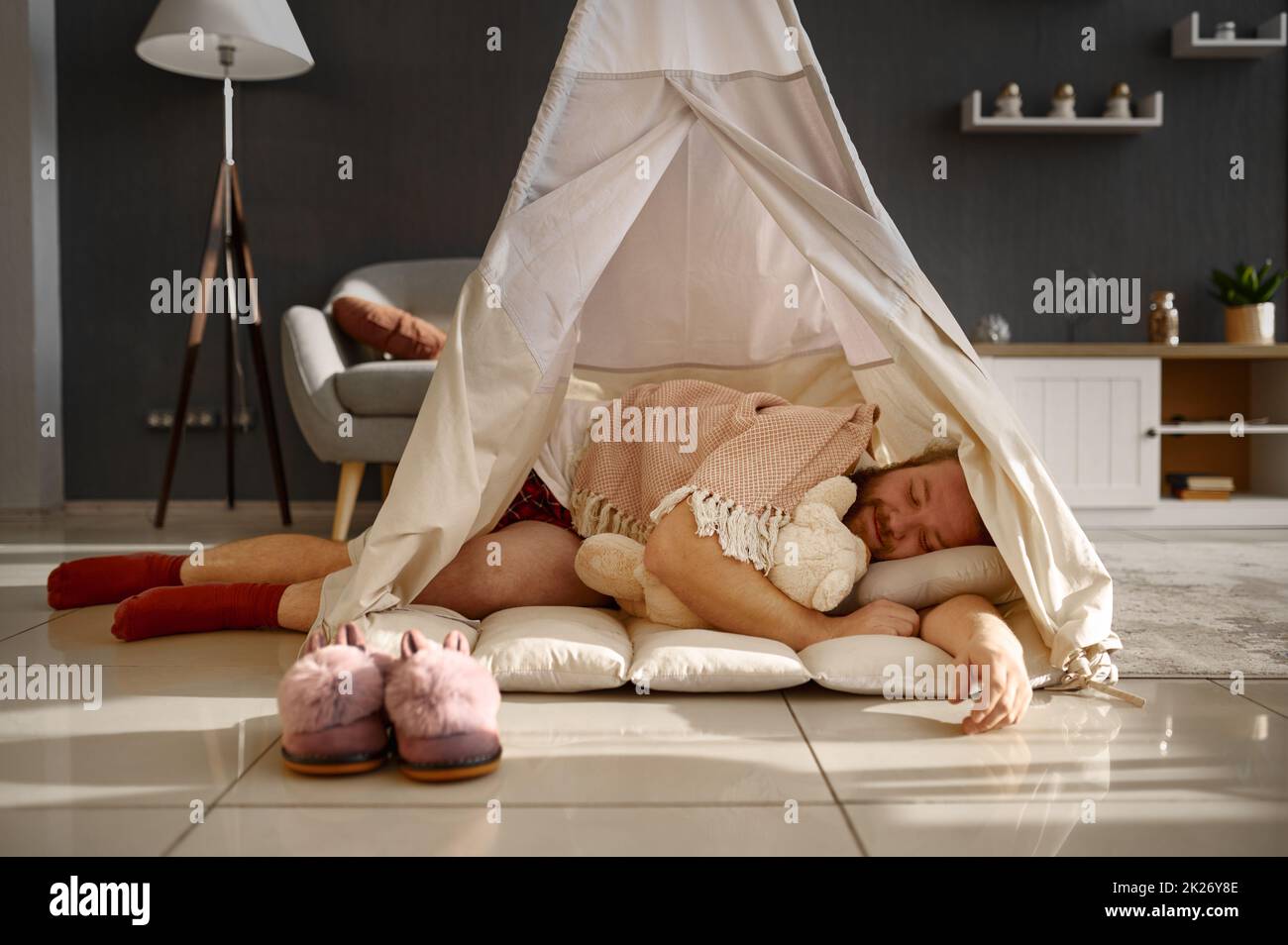 Businessman sleeping in teepee tent at home Stock Photo