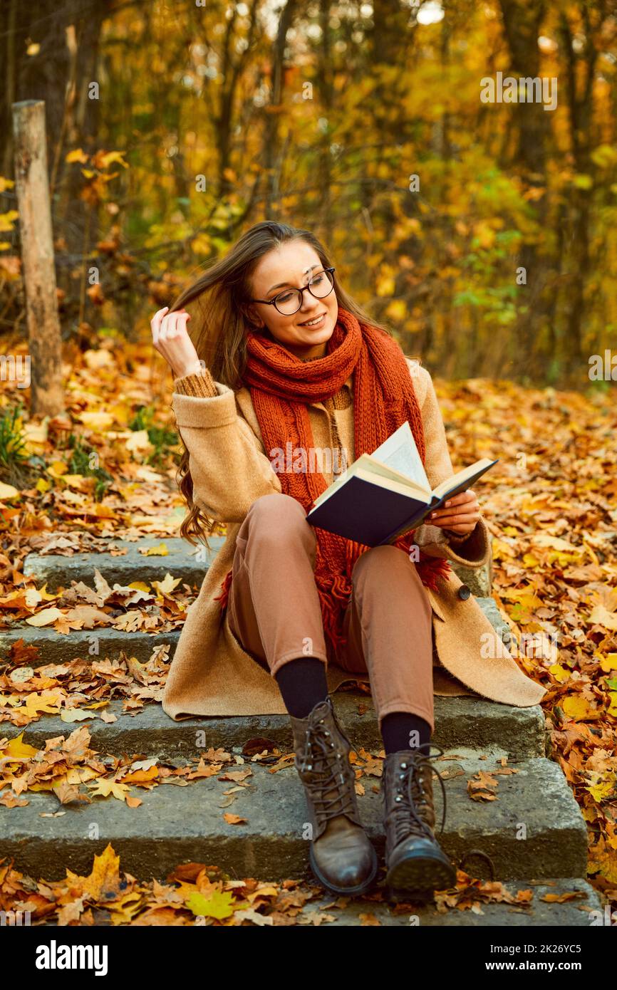 Closeup of young woman reading book outdoors Stock Photo