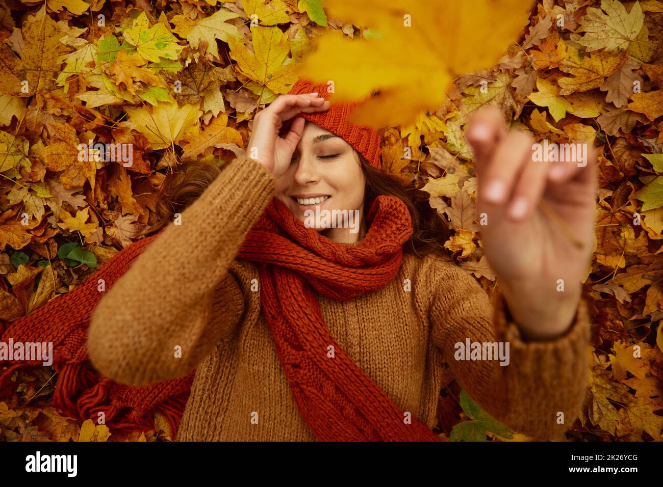 Beautiful happy woman lying on autumn leaves Stock Photo
