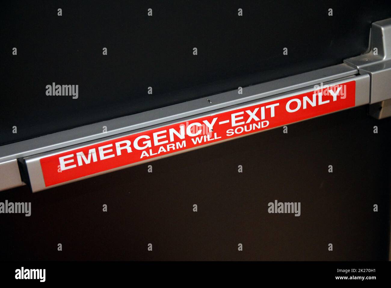 Emergency exit only alarm wall push handle on a black security door Stock Photo