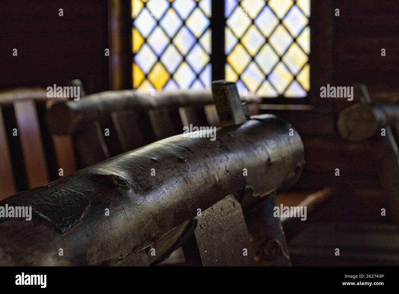 Close-up of a wooden pew inside the Chapel of the Transfiguration located in Grand Teton National Park. A stained glass window is in the background. Stock Photo